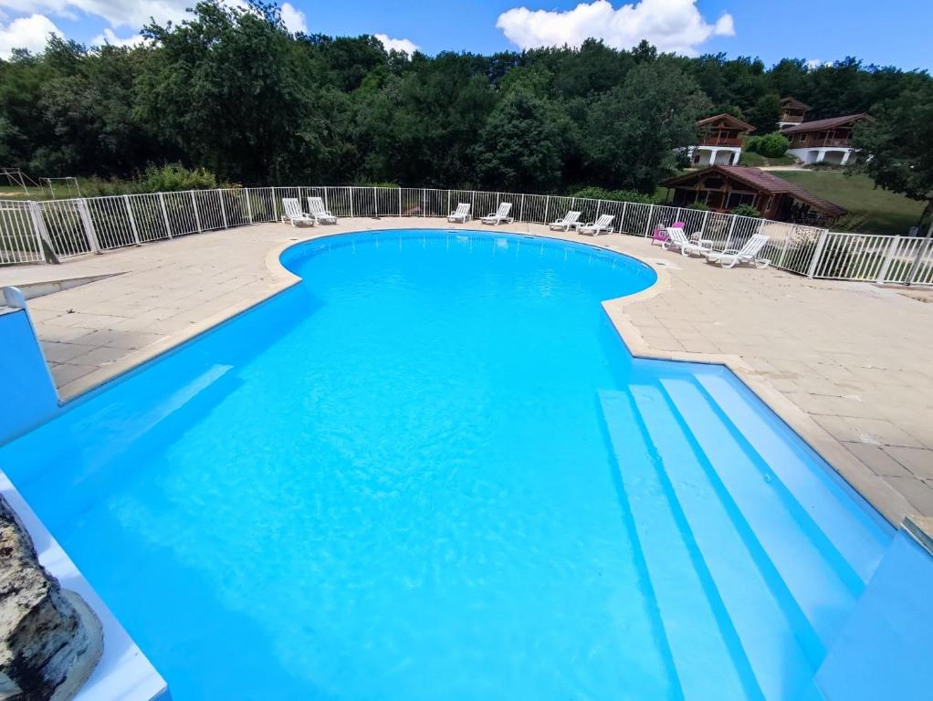 a large swimming pool with blue water at Chalet paisible à Mauroux in Mauroux