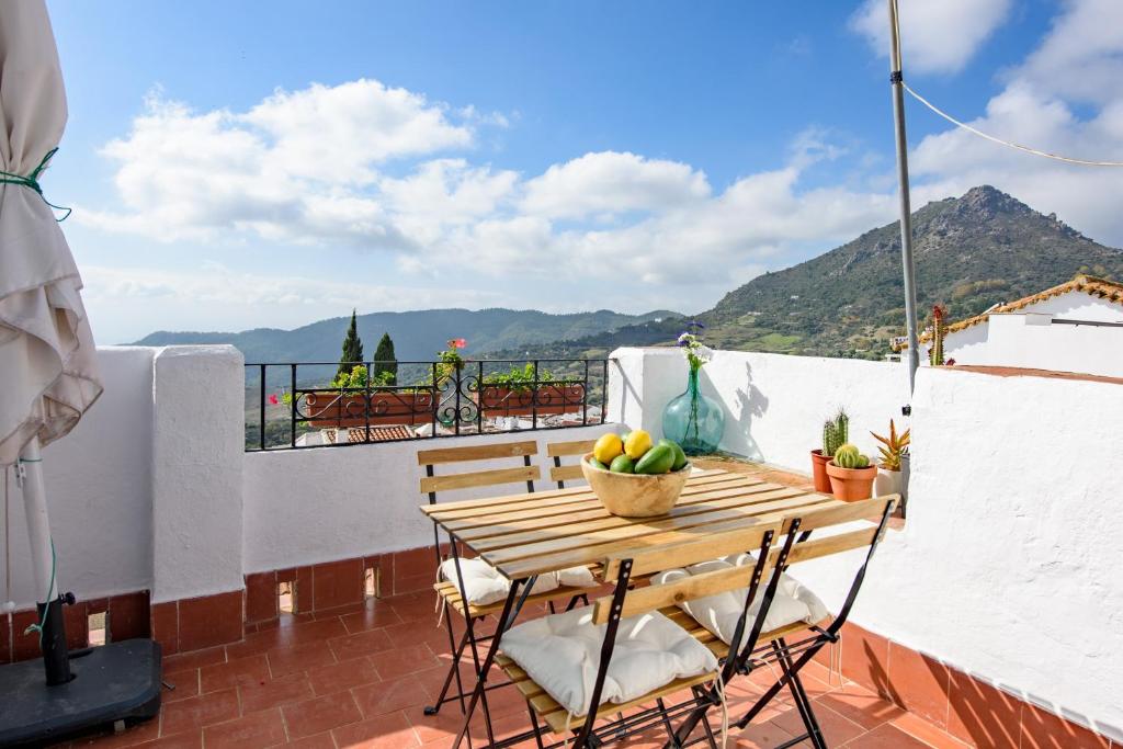 a wooden table and chairs on a balcony with mountains at La Casa De Eva in Gaucín