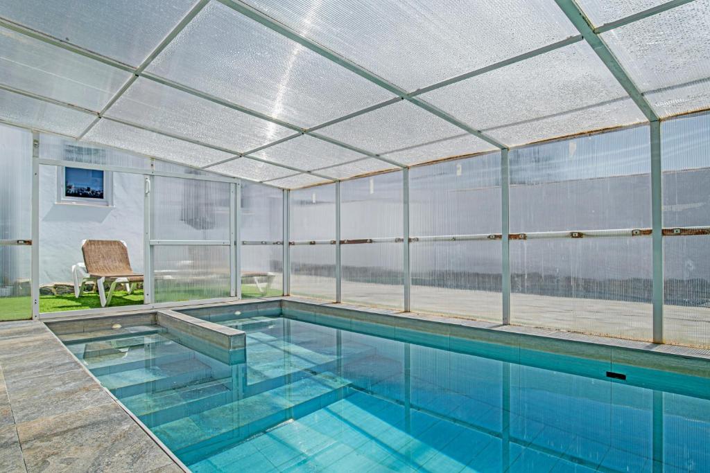 an indoor swimming pool with glass walls and a swimming pool at Casa El Elefante in La Muela