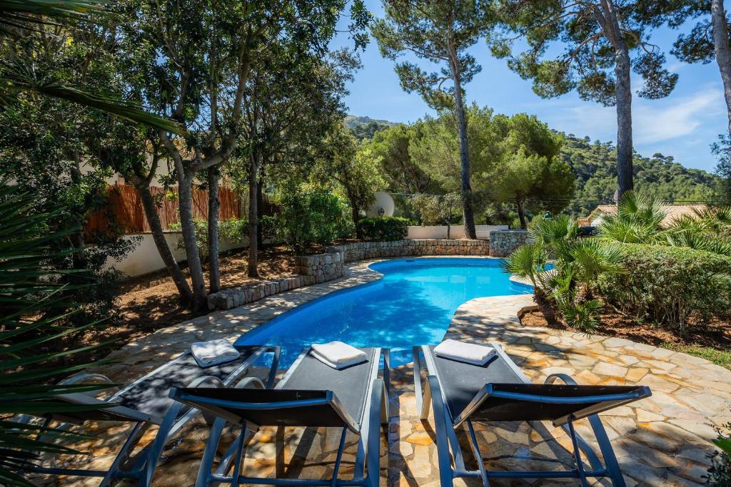a swimming pool with two chairs and a swimming poolvisorvisor at Can Domingo in Pollença