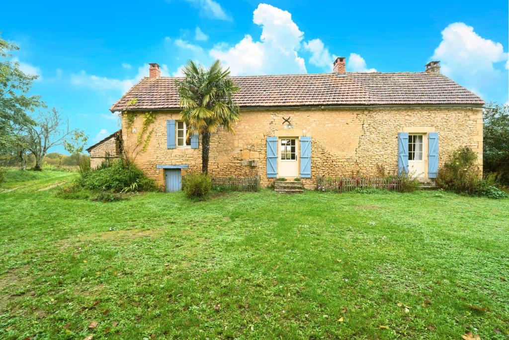 an old brick house with a palm tree in the yard at Gite La Bessede - Dordogne in La Chapelle-Aubareil