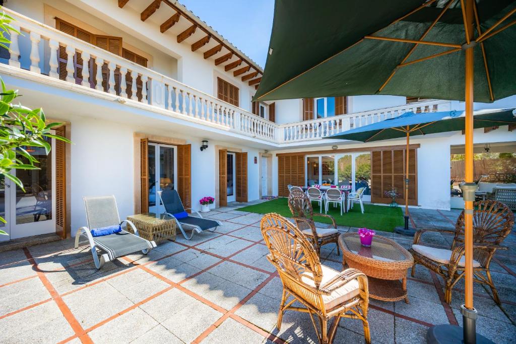 a patio with chairs and tables and an umbrella at Finca Es Pi in Llucmajor