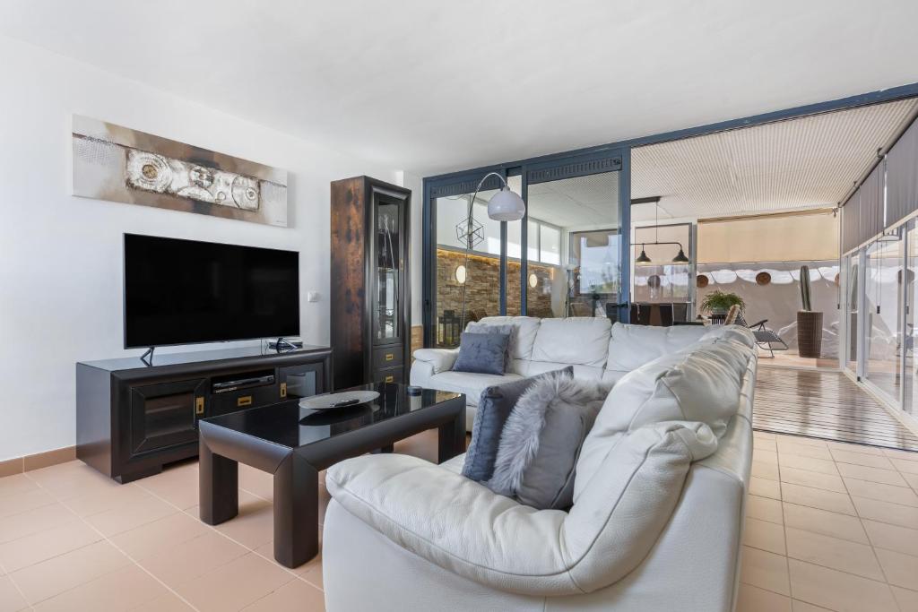 a living room with a white couch and a tv at Carmina House in Costa Calma