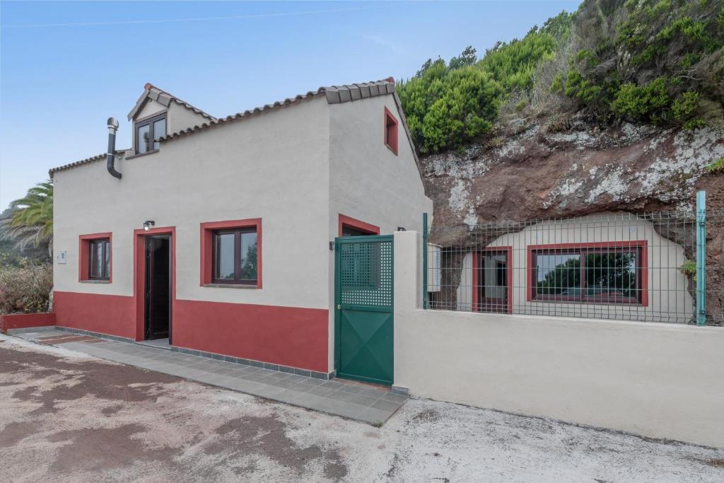 a white building with red and green doors next to a hill at Casa Efrén in Garafía