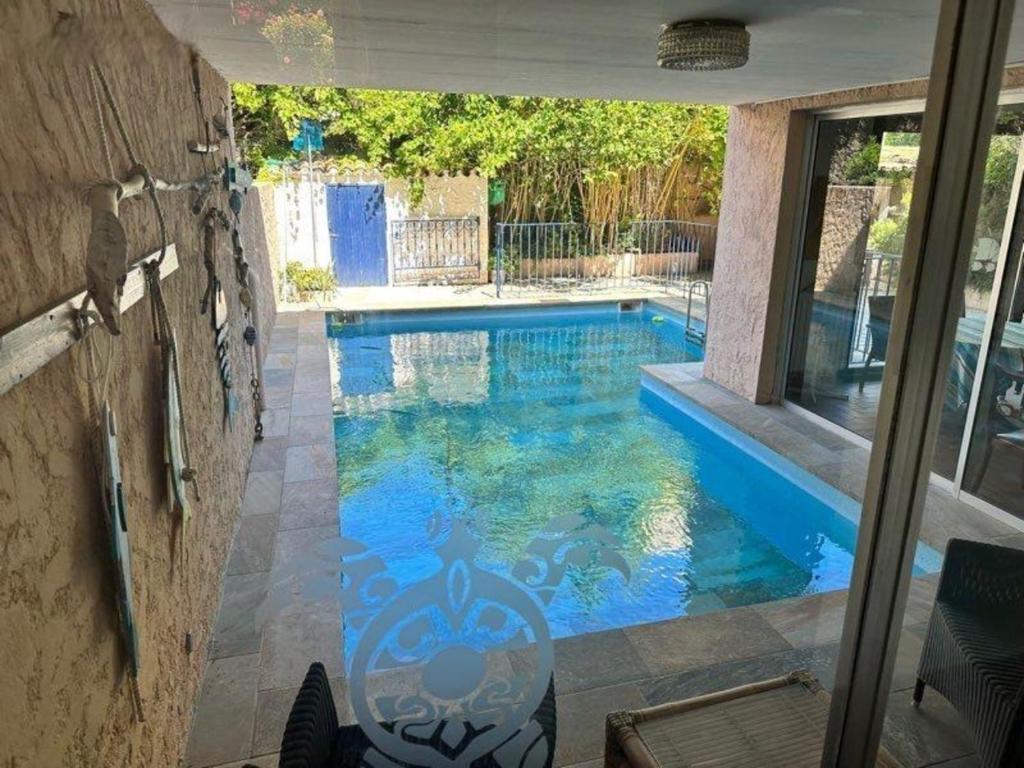 a swimming pool with blue water in a house at Villa L'Acanthe in Six-Fours-les-Plages