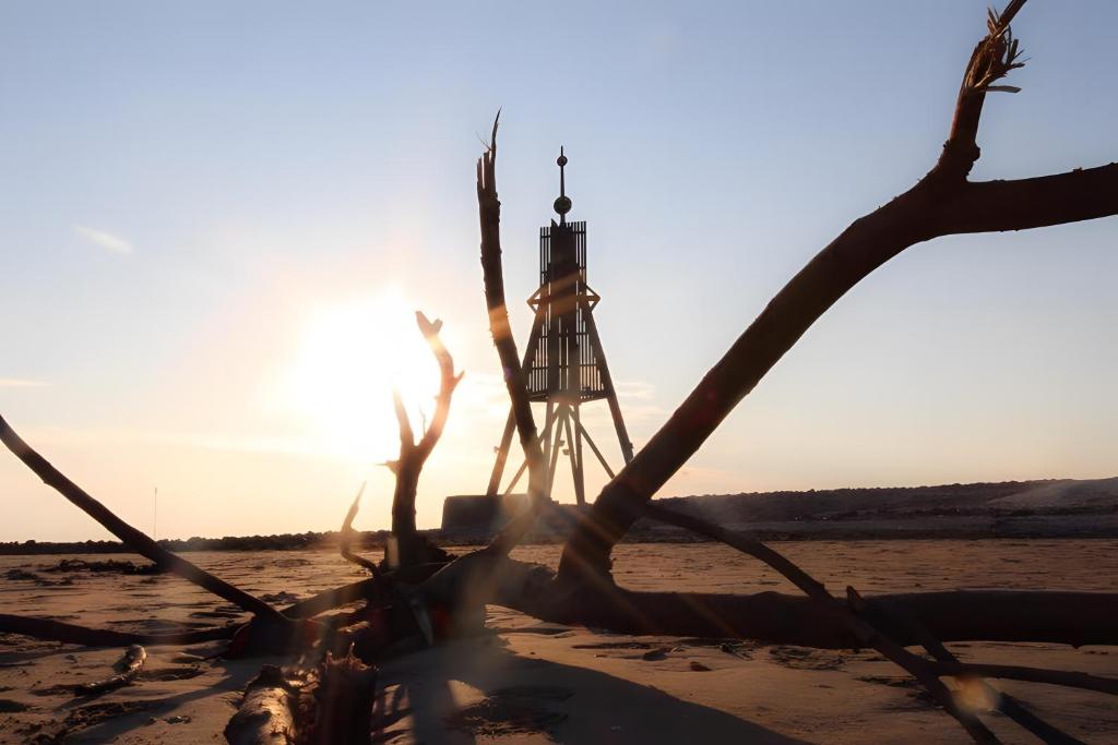 a light house on the beach at sunset at Ferienhaus Olenbrook in Cuxhaven