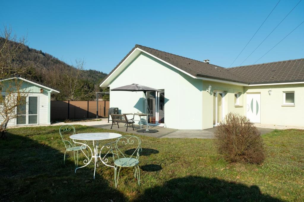 a white house with a table and chairs in the yard at Villa Green in Saint-Amé