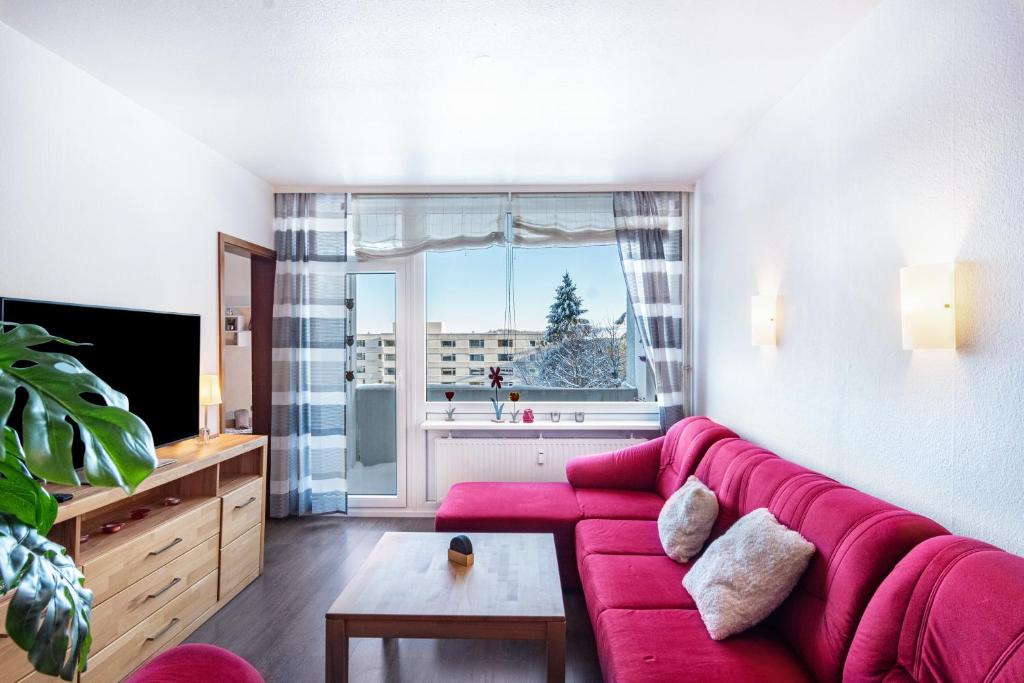 a living room with a red couch and a window at Räuberhöhle in Goslar