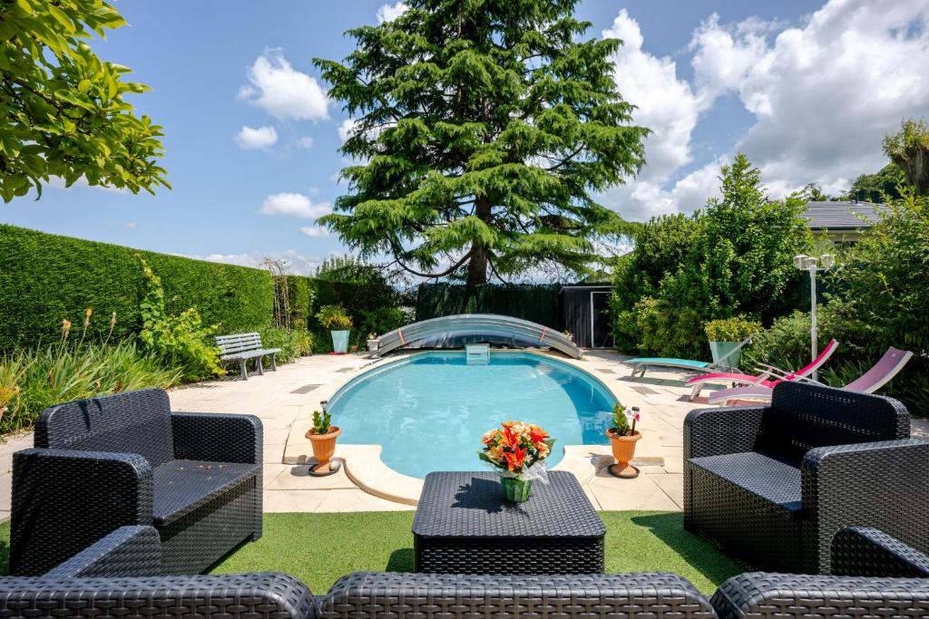 a swimming pool with two chairs and a table at Villa près du lac in Étercy