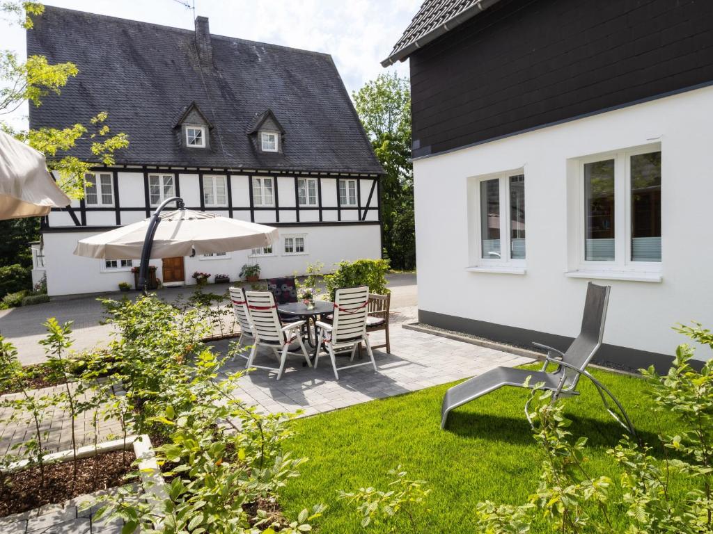 a backyard with a table and chairs and a house at Conzen Hof am Hennesee in Erflinghausen