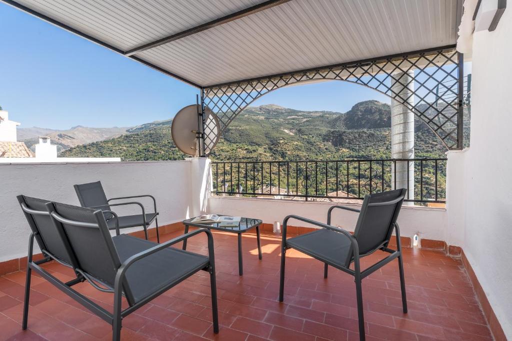 a balcony with chairs and a table and a view at Casa Ramirez in Güéjar-Sierra