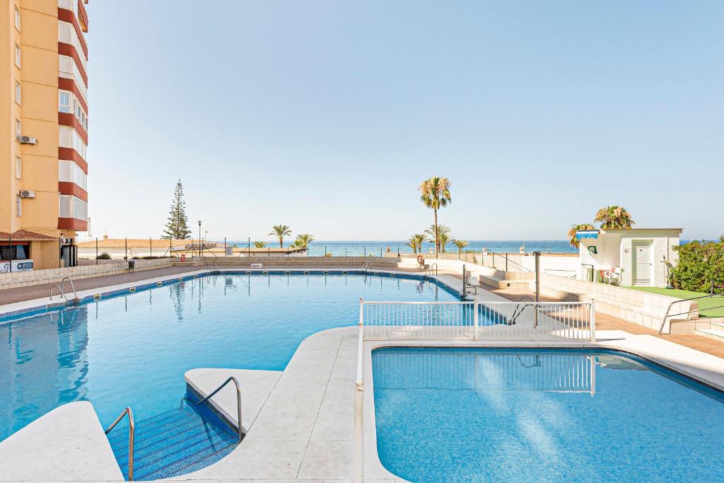 a large swimming pool with the ocean in the background at Estudios 79 in Torrox