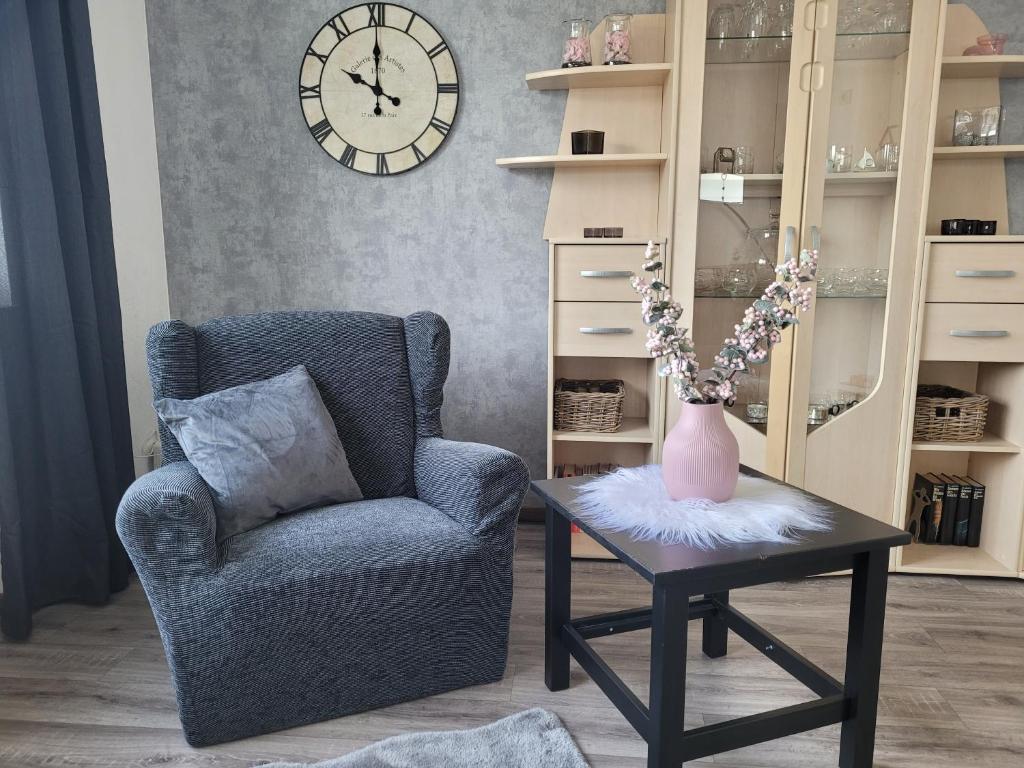 ein Wohnzimmer mit einem Stuhl und einem Tisch und einer Uhr in der Unterkunft Am Strohberg in Petersburg