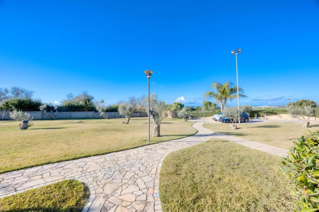 a walkway in a park with palm trees at Residence Margherita in Ugento