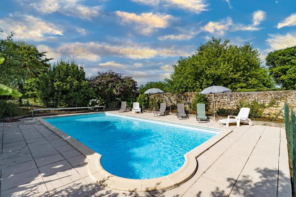 a swimming pool with chairs and umbrellas on a patio at Maison en pierre piscine clim in Varennes