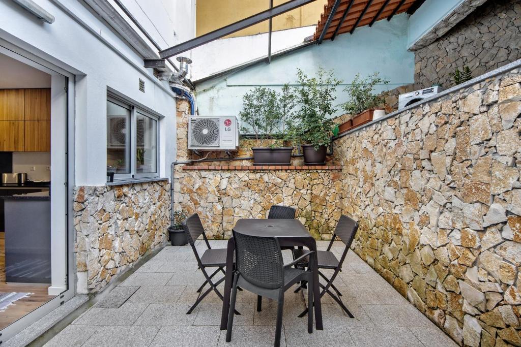 a table and chairs on a patio with a stone wall at Jm Stay in Aveiro