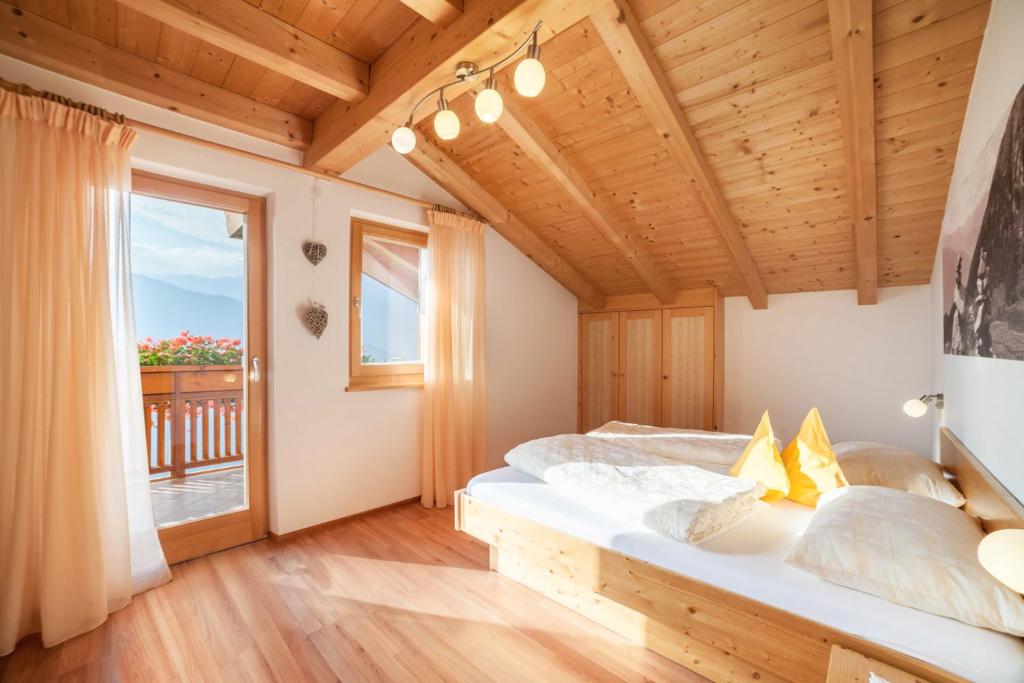 a bedroom with a large bed and a large window at Tonigbauernhof Enzian in Schenna