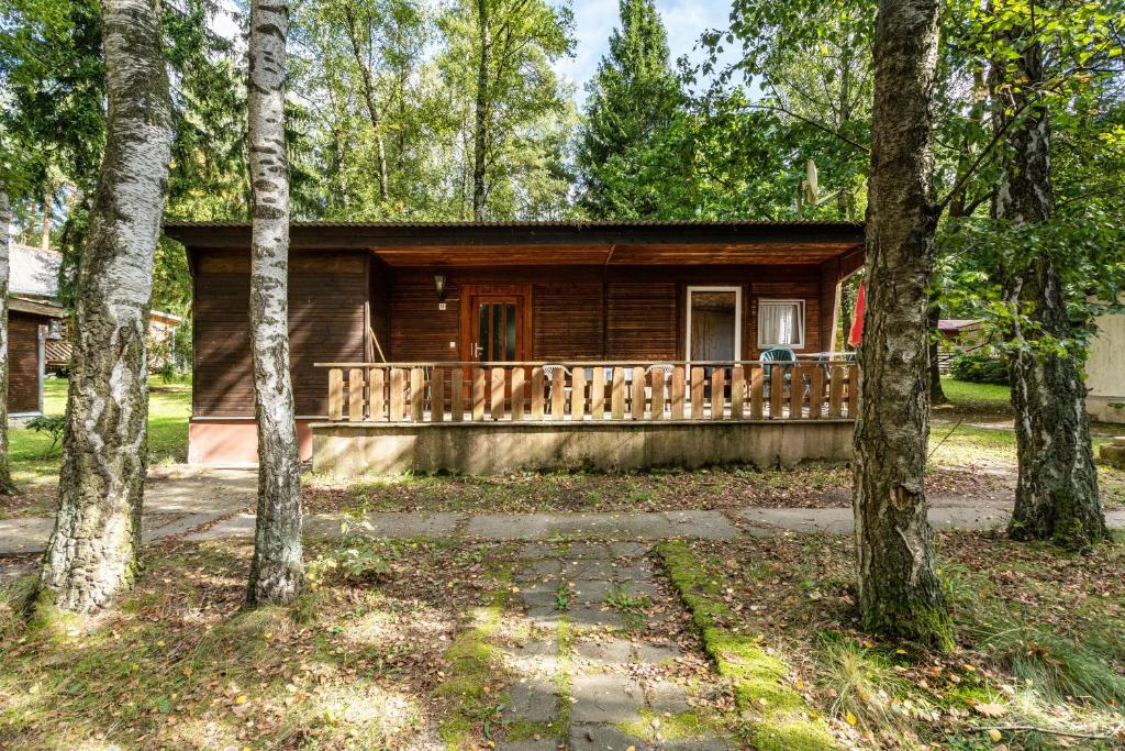 a log cabin with a porch in the woods at Bungalow 12 - Finnhütte in Niesky