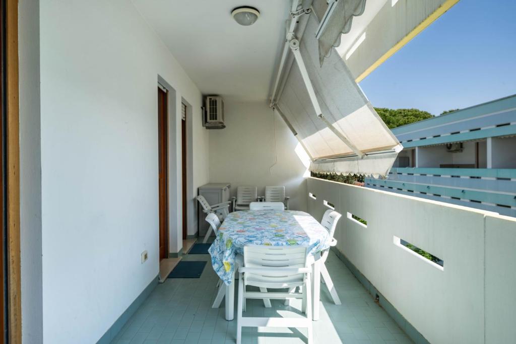 a room with a table and chairs on a balcony at Appartamento Passeggiata al Mare in Bibione