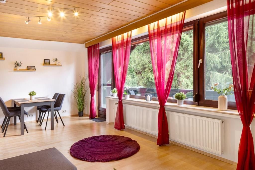 a living room with red curtains and a table at Ferienwohnung Schliestädt in Wellerode
