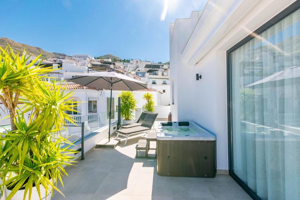 a balcony with a table and umbrella on a building at Luxury apartment in Cómpeta in Cómpeta
