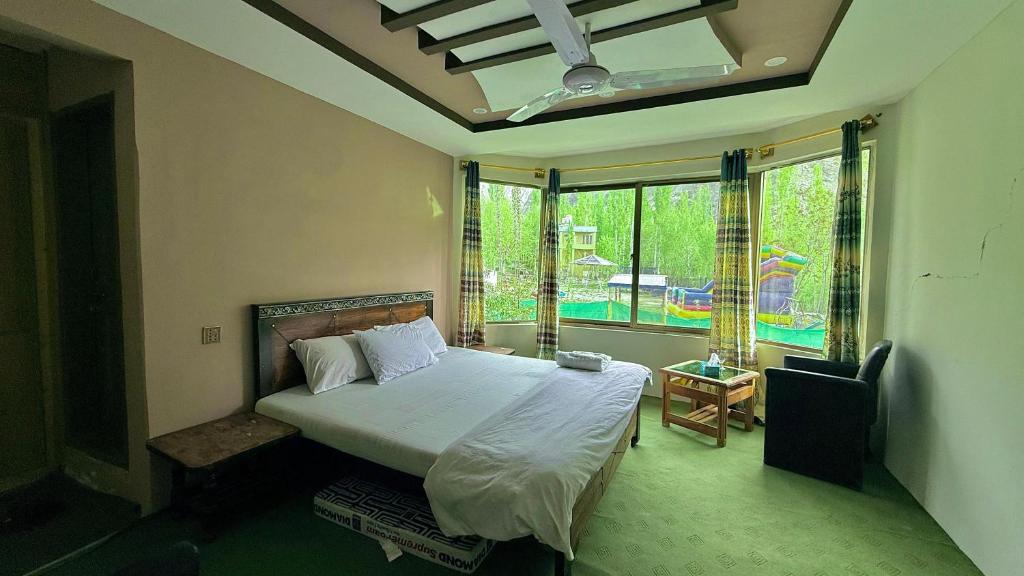 a bedroom with a bed and a large window at Flora Inn Skardu in Skardu