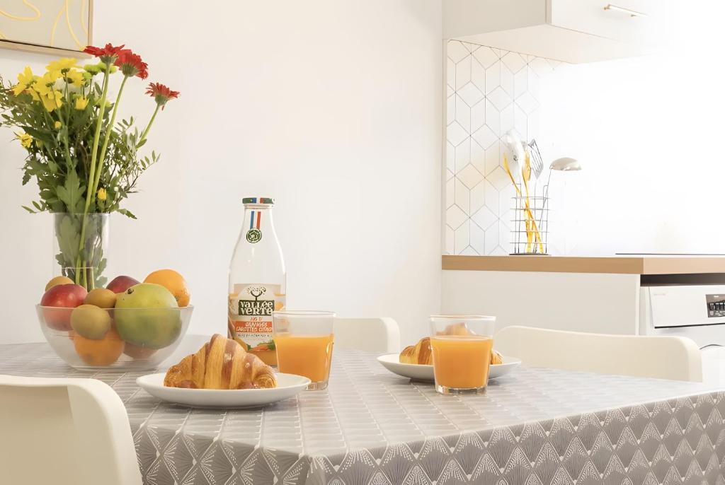 a table with a bowl of fruit and a bottle of orange juice at L'ilot Narossais - Conciergerieland in Narrosse