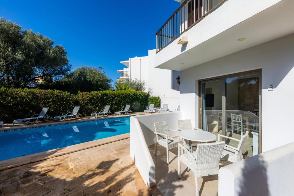 a patio with a table and chairs next to a swimming pool at Apartamento Bon Aire N3 in Cala Ferrera