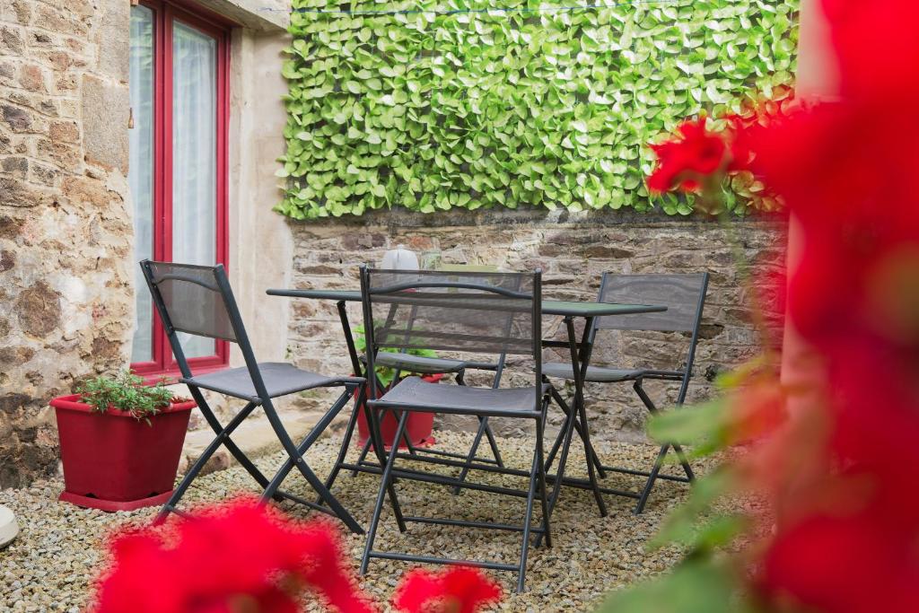 a table and chairs in front of a brick wall at Le Douar Armor - cour intérieure in Dinan