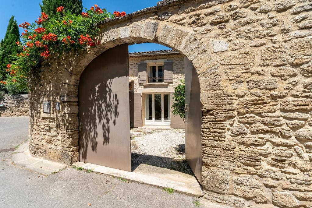 a stone house with an archway in front of a building at Mazet de Cabrières Gordes, Clim in Cabrières-dʼAvignon