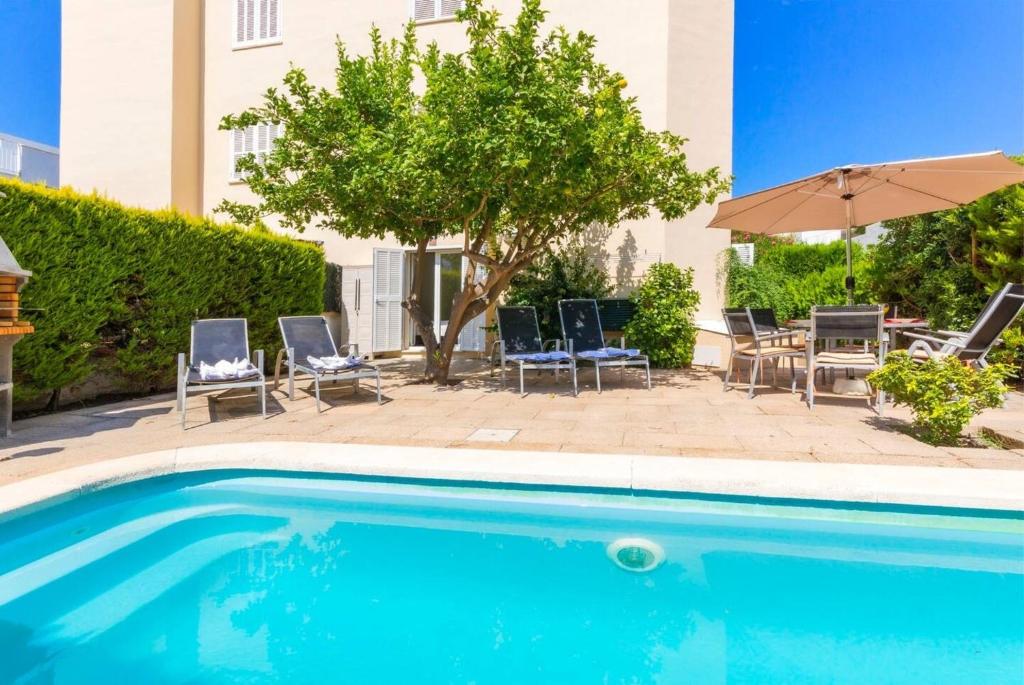 a swimming pool with chairs and an umbrella at Playamar in Alcudia