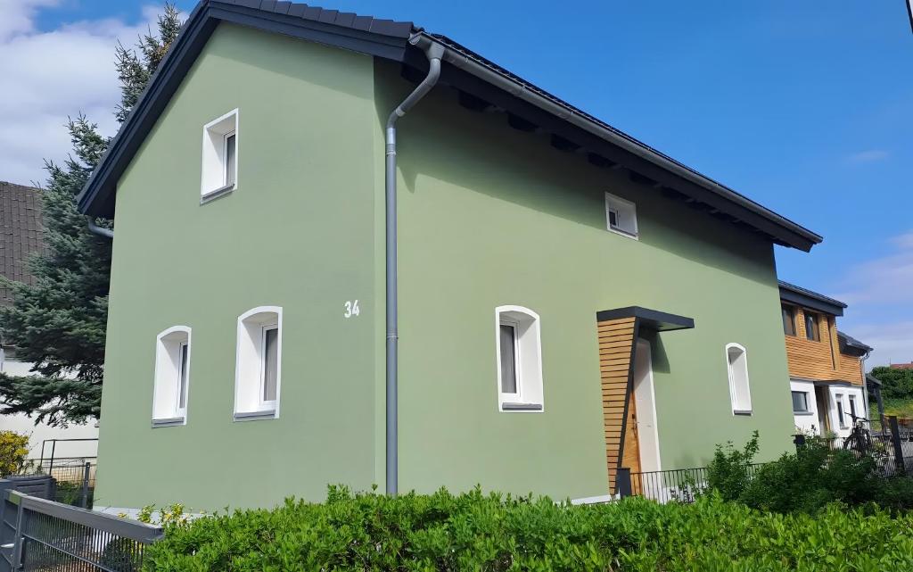 ein grün-weißes Haus mit schwarzem Dach in der Unterkunft Hümmer Chalets in Breitengüßbach