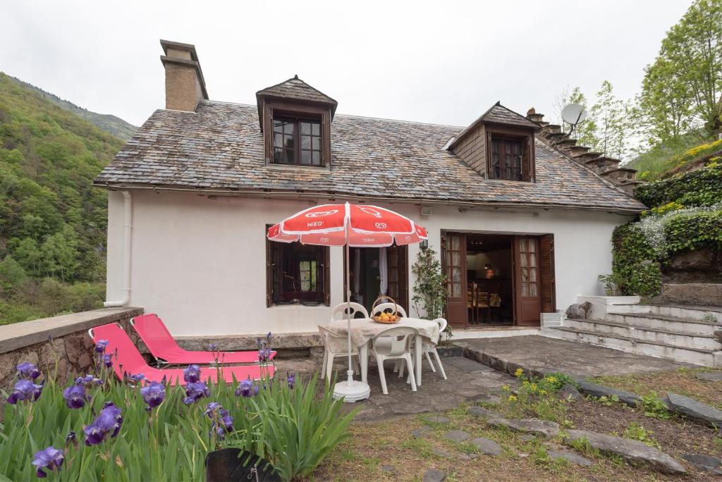 a house with a table and chairs and an umbrella at Cottage au Calme in Gèdre