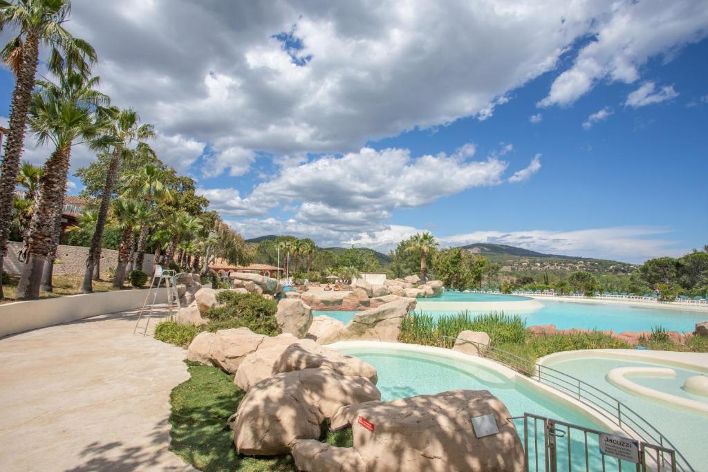 a swimming pool in a resort with trees and water at Restanques de Saint Tropez - arums in Grimaud