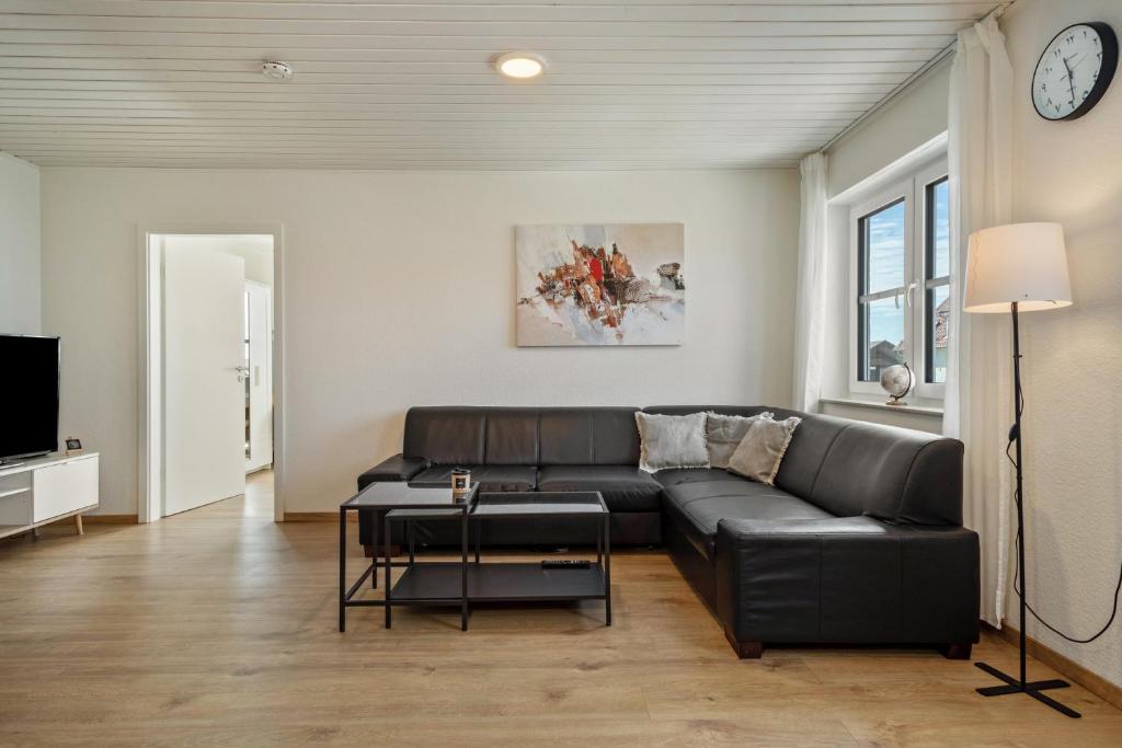 a living room with a black leather couch and a tv at Bodenseenest in Meckenbeuren