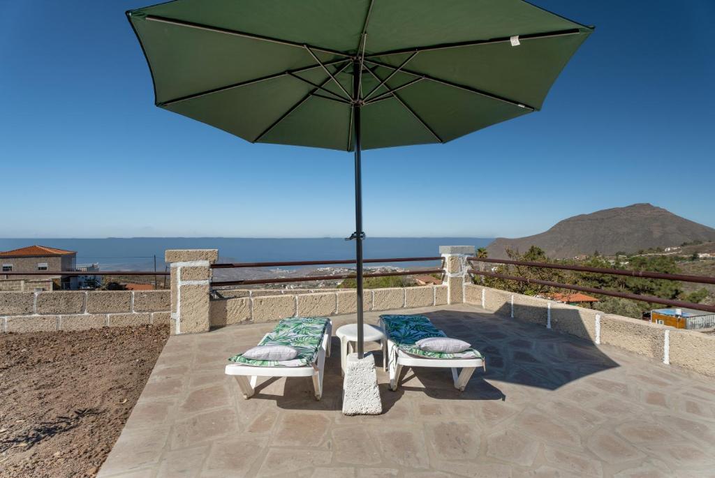 two chairs and an umbrella on a patio at Casa Eyden Sunset View in Arona