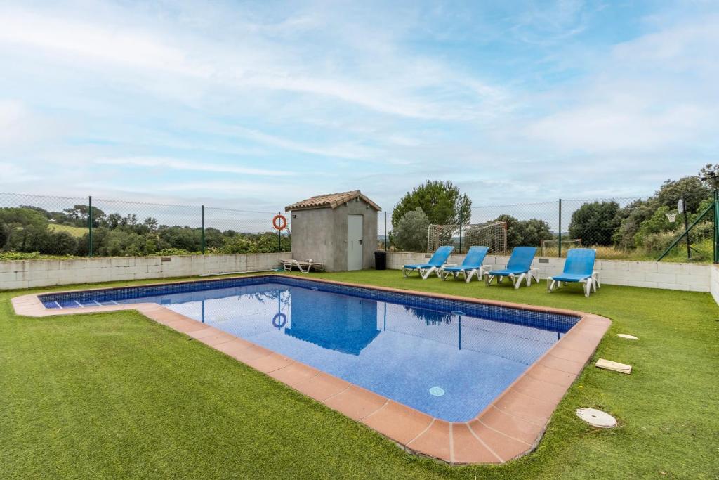 a swimming pool on a lawn with chairs and a house at Cal Viudet in Caserras