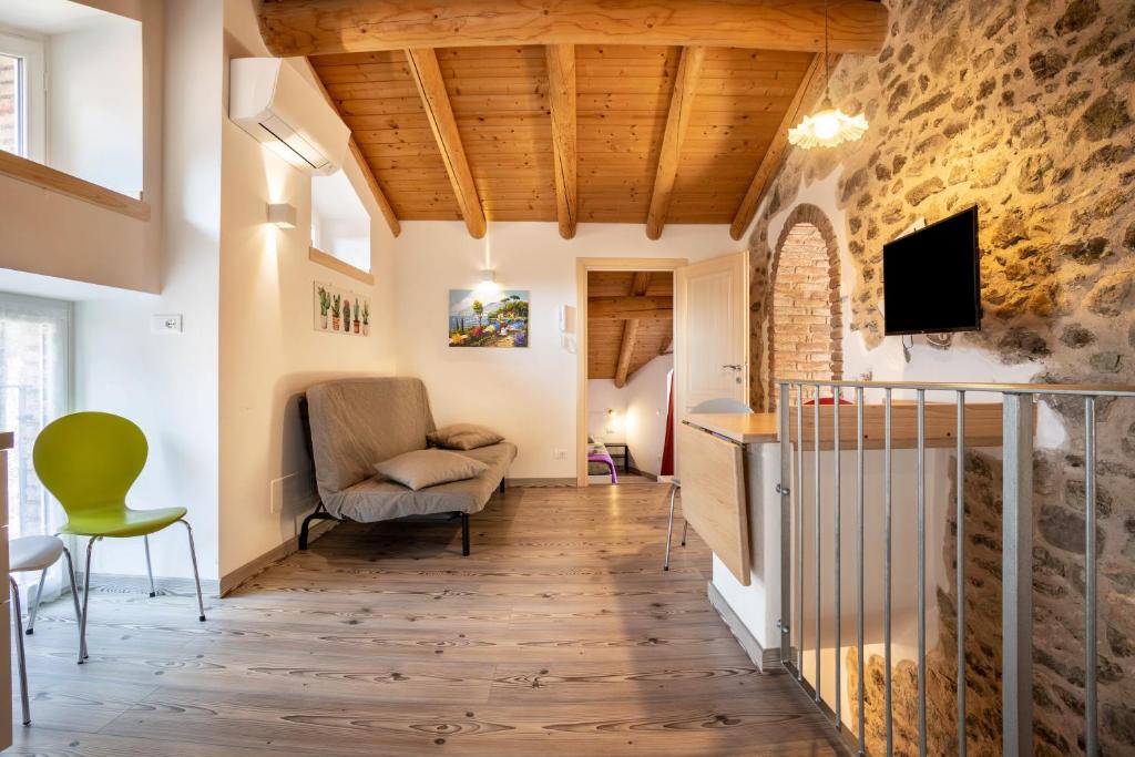 a living room with a stone wall and a chair at Appartamento Gufo in Tremosine Sul Garda