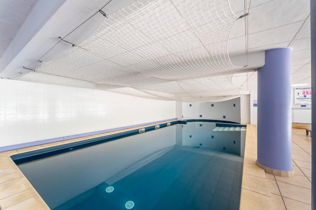 a swimming pool in a building with a ceiling at Appartement des Cedres in Uzès