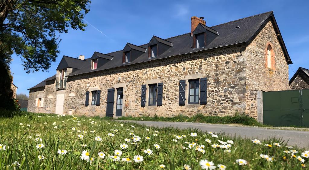a stone building with a black roof on a field of flowers at Gîte Bonaty in Soulgé-sur-ouette