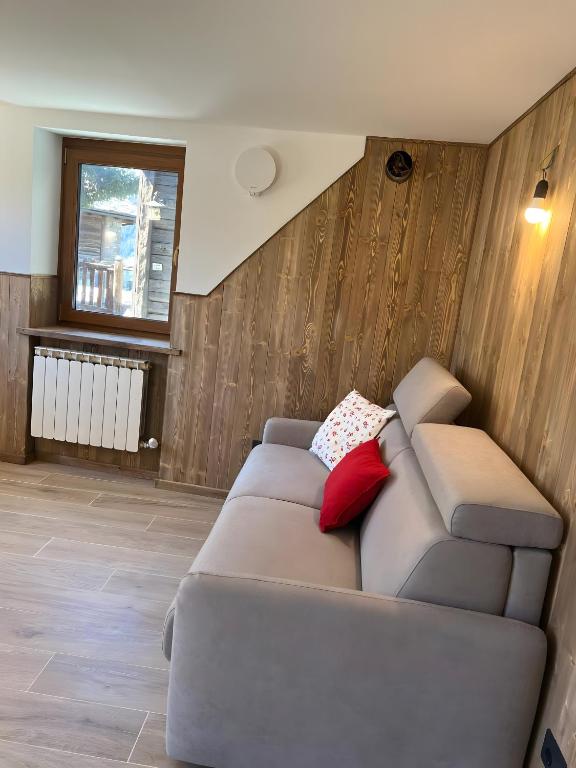 a living room with a gray couch with red pillows at L’Angolo del Paradiso in Cogne