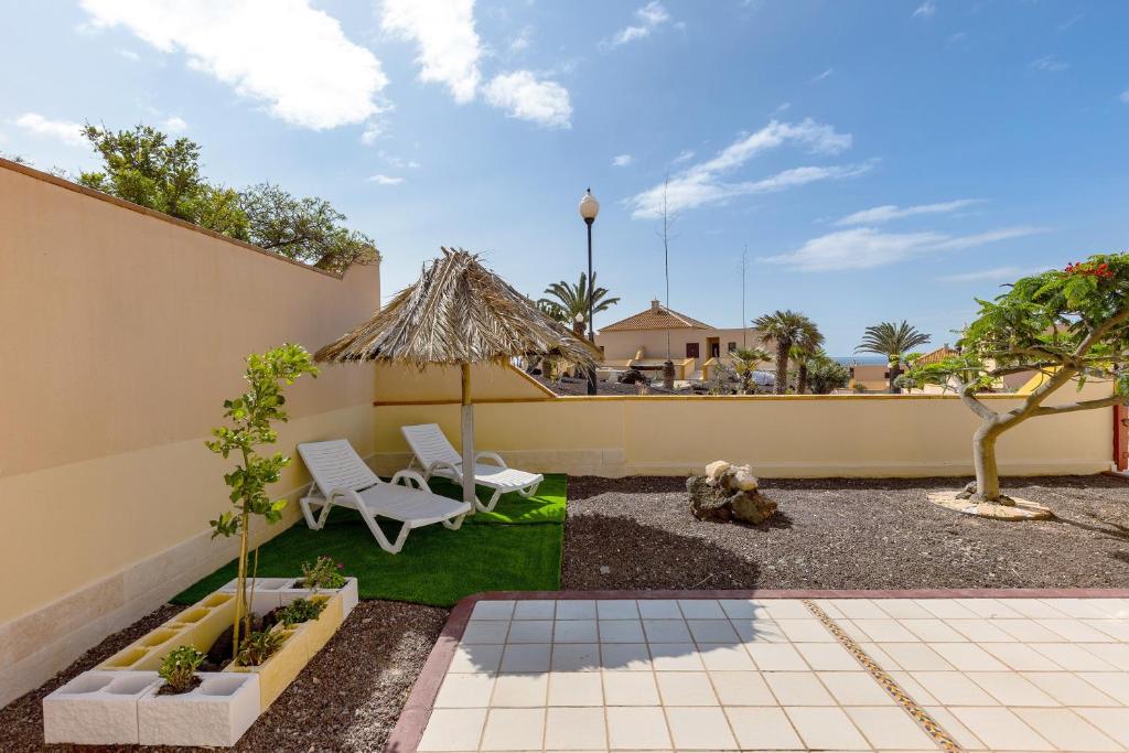 a patio with two chairs and a umbrella at Te Mahana Nei House in Costa Calma