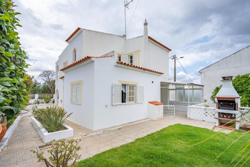 a white house with a garden and a fireplace at Villa Raposo em Porches in Porches
