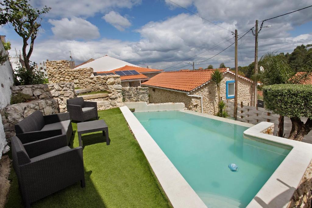 a swimming pool with two chairs in a yard at Moradia dos Castelos Amarelo in Santarém