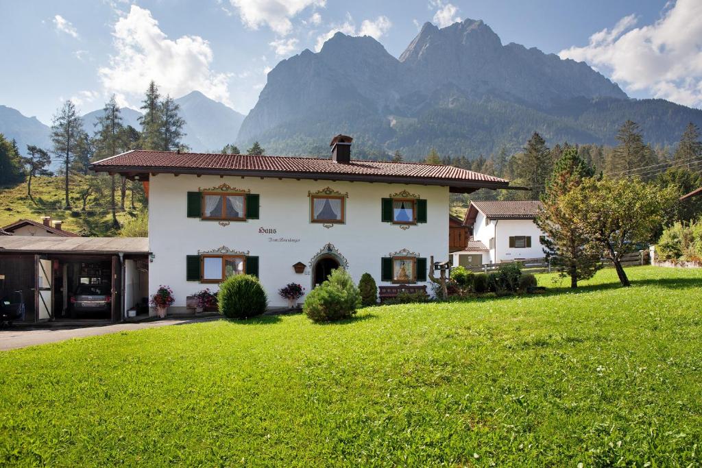 a house in a field with mountains in the background at Ferienwohnung Waxensteinblick in Grainau