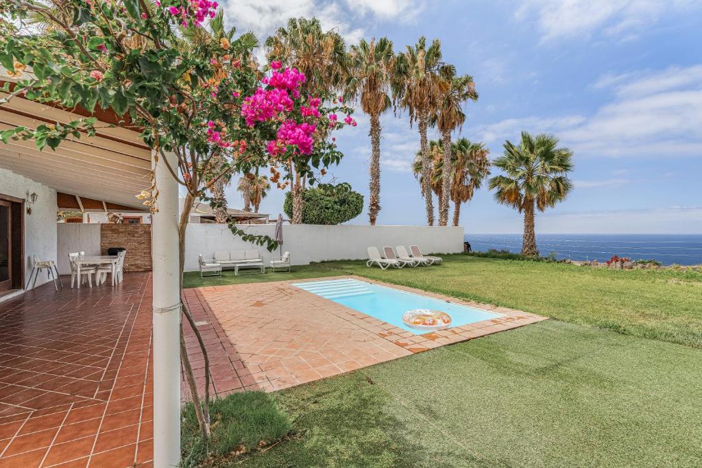 a backyard with a swimming pool and palm trees at Villa Cassis in Adeje