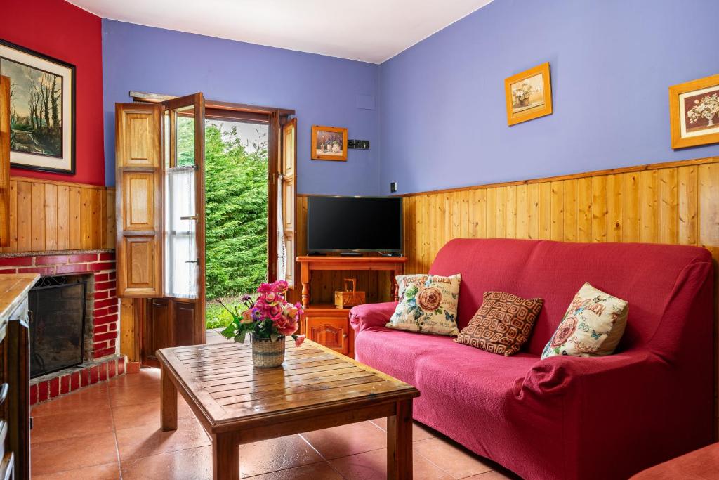 ein Wohnzimmer mit einem roten Sofa und einem Tisch in der Unterkunft Socastillo C in Fresnedo
