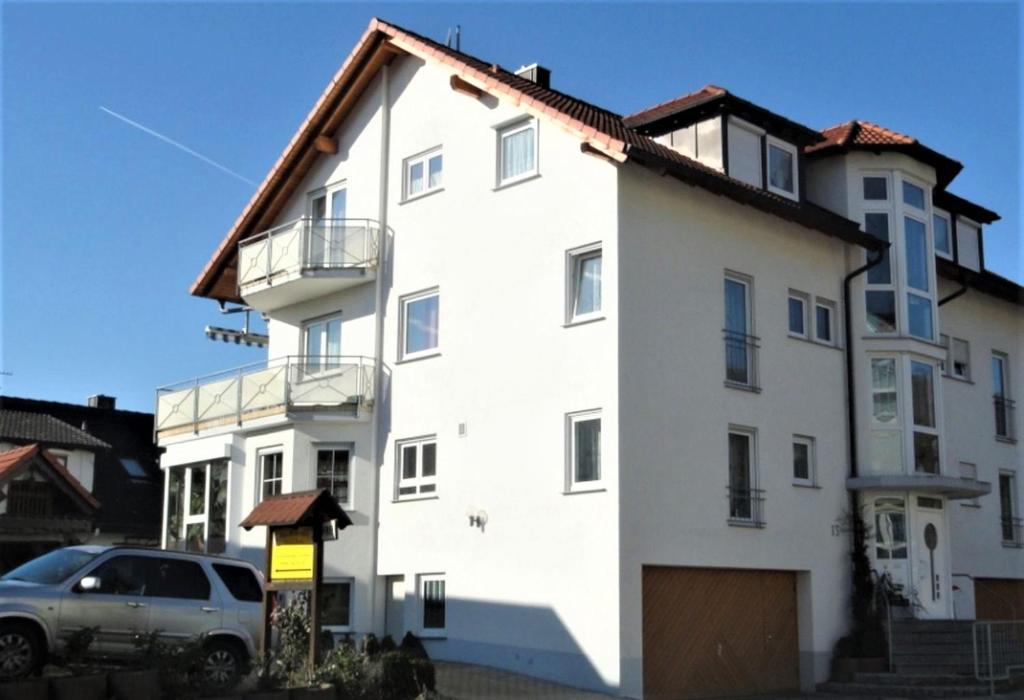 a white house with a car parked in front of it at Haus Zum Haiden in Bodman-Ludwigshafen
