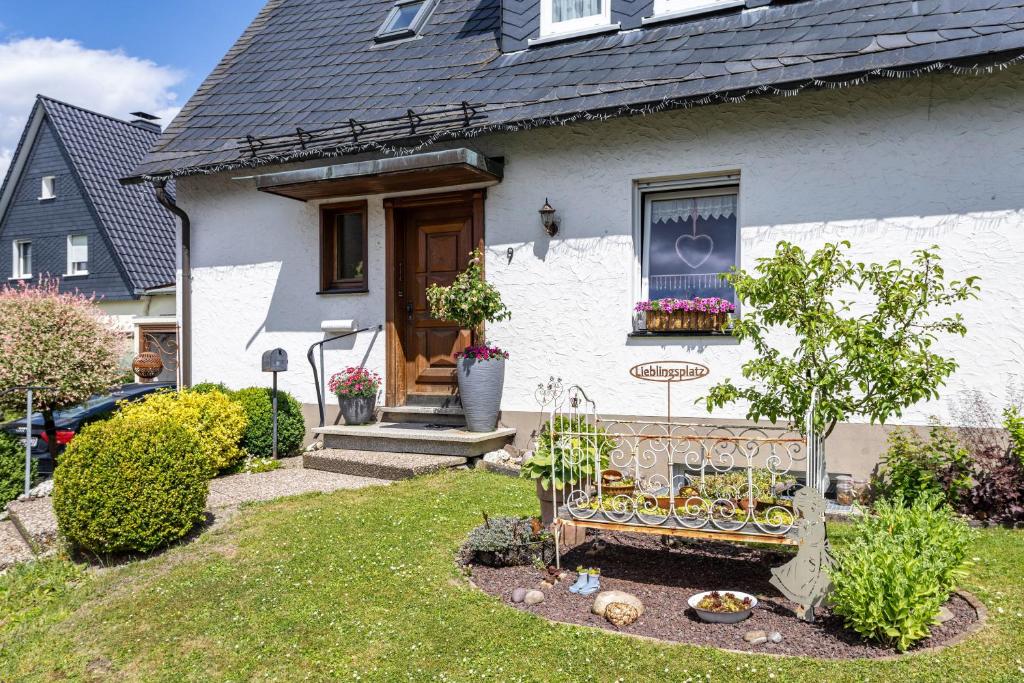 a white house with a bench in the yard at Annes Stübchen in Schmallenberg