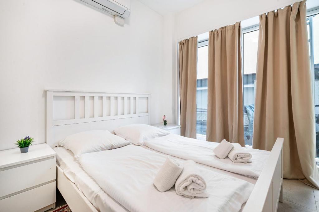 a white bedroom with a bed with white sheets and towels at Aldars Urban Trio Suite Nr. 9 in Munich